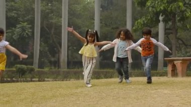 Parkta kolları havada koşan çocukların stok videosu.