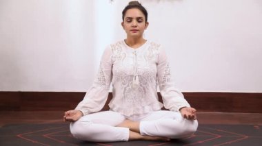 Beyaz elbiseli bir kadının Bhramari Pranayama yoga egzersizi yaptığı video kaset.