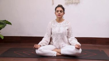 Beyaz kıyafetli bir kadının derin nefes alma egzersizi videosu.
