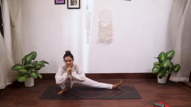Beyaz elbiseli bir kadının yan hareketlerini gösteren video (Skandasana)
