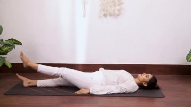 Kadının alternatif bacak hareketi videosu Ardha Halasana, bu egzersiz uyluk ve kalça kaslarını güçlendirir