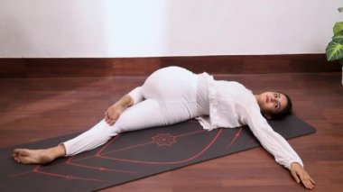 Sırtüstü Omurga Bükme (Supta Matsyendrasana) adlı kadının videosu, omurga ve kuadriseps kaslarının gerilmesine yardımcı olur.