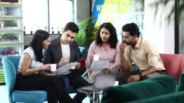 Neşeli ofis çalışanları şirket projesini tartışıyor ve konferans odasında kahve içiyor.