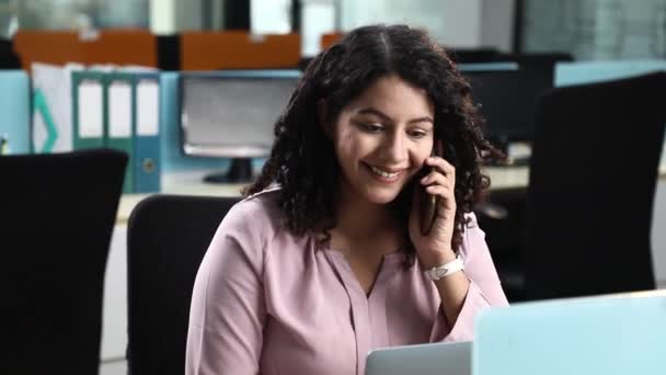 在办公室用笔记本电脑用手机聊天的年轻女性员工的股票视频 — 图库视频影像