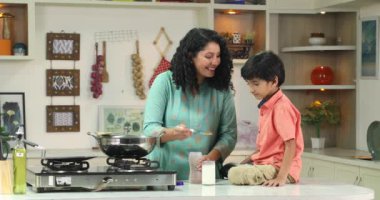 Anne oğluna bir bardak süt veriyor.