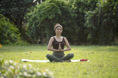 Aktif kıyafetli hoş bir kadın parkta bacak bacak üstüne atmış oturuyor.