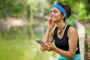 Spor kıyafetli genç bayan bahçede müziğin tadını çıkarıyor.