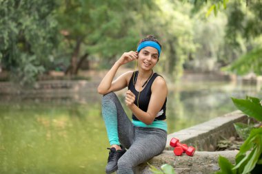 Güzel bayan antremandan sonra dinleniyor kulaklıkla müzik dinliyor.