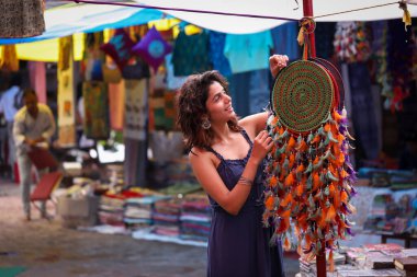 Pazar pazarındaki neşeli model Yeni Delhi pazarındaki dekorasyon parçasına bakıyor.