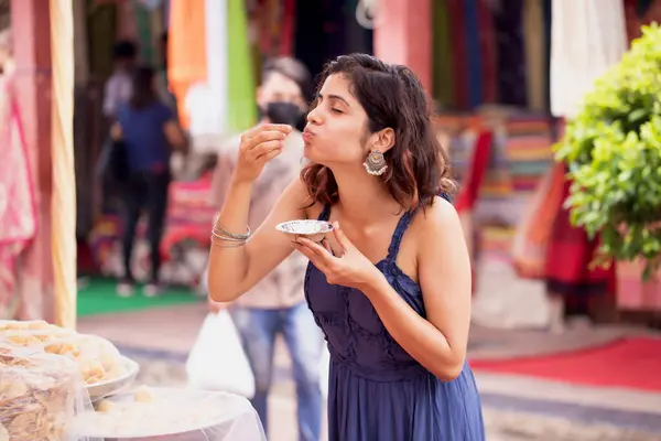 stock image Woman enjoying eating indian snack pani puri on street