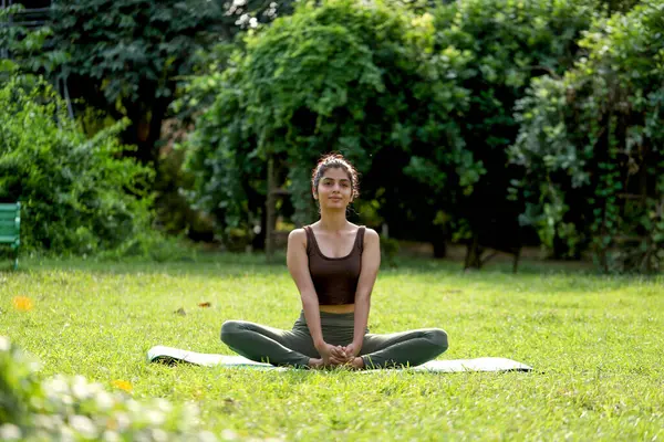 Kelebek yogası (Baddha Konasana Egzersizi) yapan zarif bir kadın parkta poz veriyor