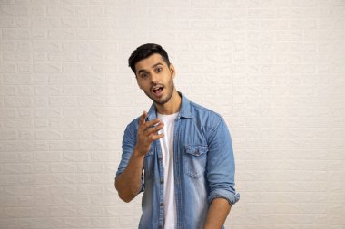 Şaşırmış muhteşem adam beyaz arka planın önünde kamerayı işaret ediyor.