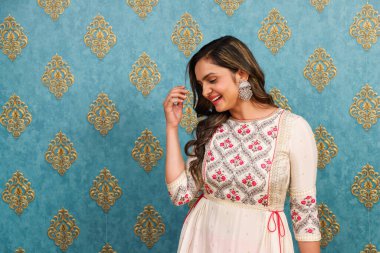 Gülümseyen bir kadın, başka tarafa bakarken, Hint kıyafeti giymiş.