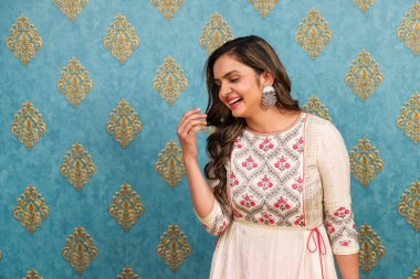 Yüzü kızaran ve poz veren gülümseyen bir bayan, Hindistan kıyafeti giymiş.