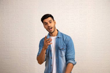 Şaşırmış muhteşem adam beyaz arka planın önünde kamerayı işaret ediyor.