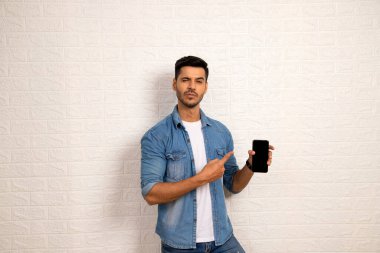 Kot tişörtlü şık adam telefonu gösteriyor ve onu işaret ediyor. Kötülük Konsepti