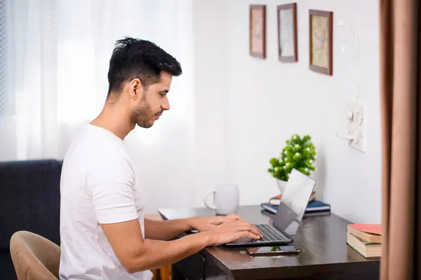 Evdeki oturma odasında oturan bir adam dizüstü bilgisayarla çalışıyor.