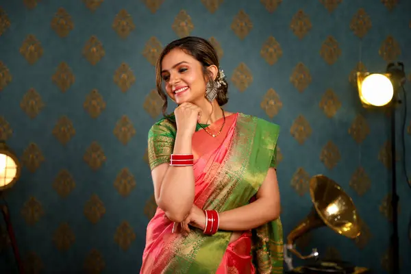 stock image A cute female model wearing an Indian saree sits down and smilesin front of the camera while posing on a chair