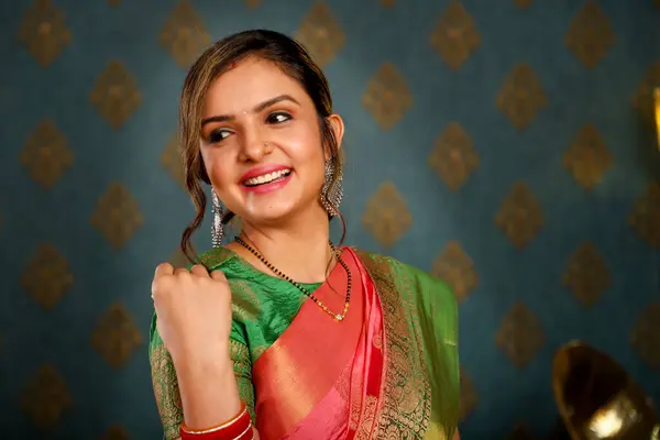一位穿着印度萨里衫的可爱女模特坐在椅子上 在摄像机前微笑着 免版税图库照片