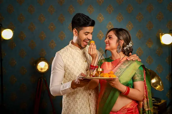 这对可爱的情侣穿着传统的印度服装 在镜头前吃着瓢虫 准备参加Diwali节 图库图片