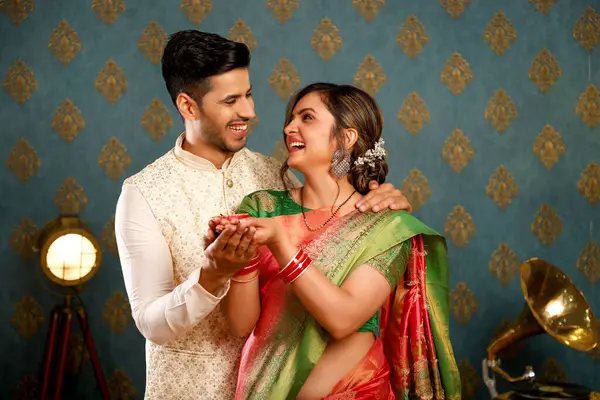 Diwali festivali için geleneksel kıyafetler giyerken ellerinde para tutan güzel bir çiftin fotoğrafı.