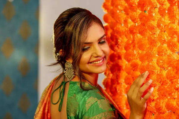 Muhteşem genç bayan Diwali kutlamaları sırasında çiçeklerle kaplı duvarın yanında duruyor.