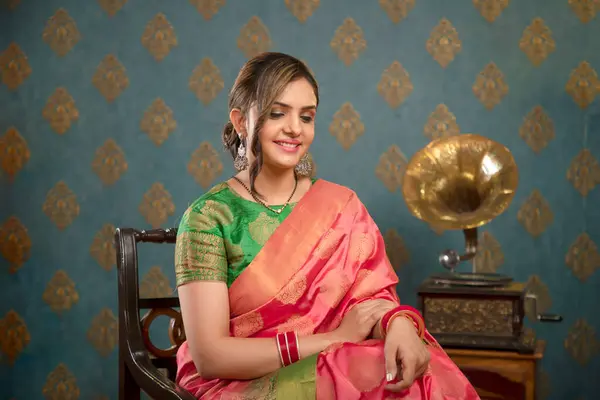 Diwali kutlamasında sandalyede otururken kameraya poz veren sari giymiş güzel bir kadın.
