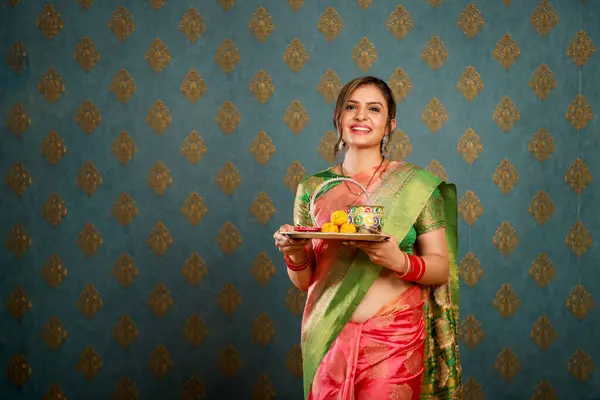 stock image A gorgeous woman in a saree holds a plate in her hand while smiling and looking towards camera