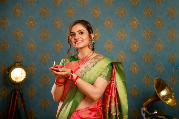 图为一名无辜的年轻女子 穿着传统的印度服装 在灯会上微笑着举杯 图库图片