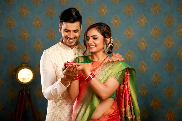 图为一对穿着传统印度服装的快乐夫妇在庆祝Diwali时持着Diya的照片 图库照片