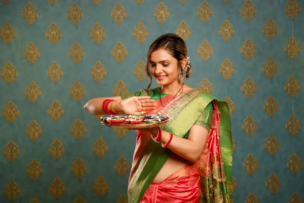 图片中的一位年轻貌美的女士穿着传统的印度服装 拿着一个盛满迪亚斯的盘子庆祝Diwali的到来 免版税图库图片