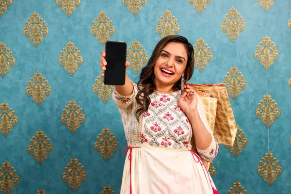 一个穿着传统印度服装的漂亮女人在摄像机前展示手机画面 图库照片