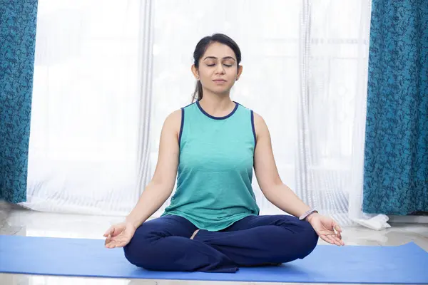 Evde meditasyon yapan bir kadın.