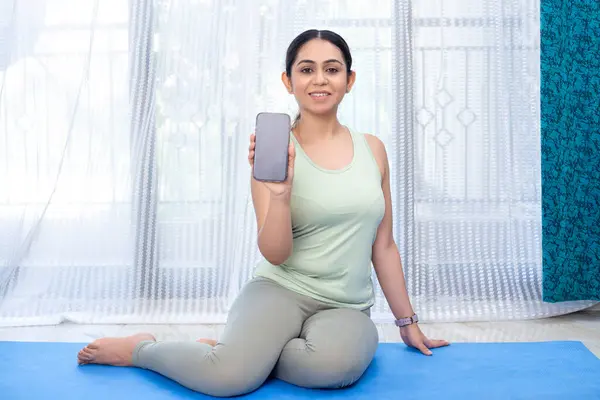 Çekici kadın kameraya akıllı bir telefon ekranı gösteriyor. 