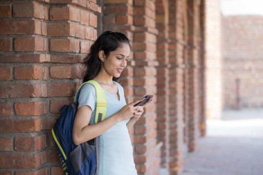A cute female student wearing sky blue using a mobile phone