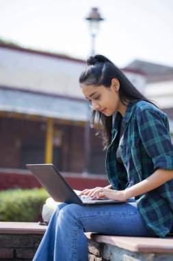 Single woman working on her laptop on the college campus