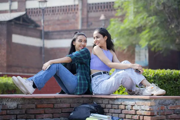 Attractive womans are sitting and staring at each other in the university park.