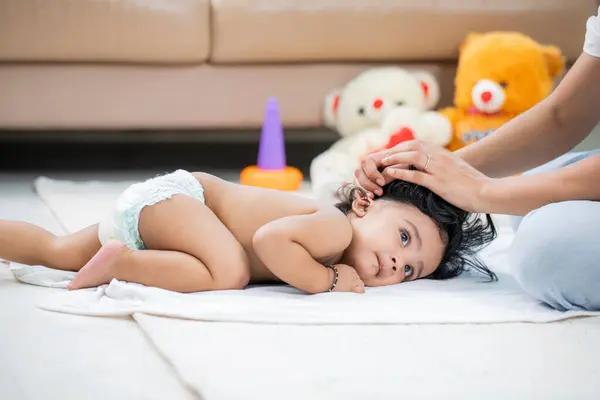 Sevimli bebek yerde yatıyor ve annesi el üstünde hareket ediyor.