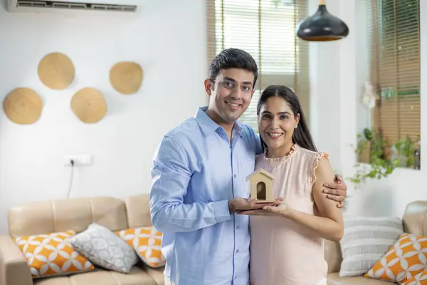 Havalı bir çift oyuncak evi elinde tutuyor. Kredi kavramı