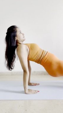 Spor yaparken omuzlarını, göğsünü ve bileklerini geren ve kollarını ve bacaklarını güçlendiren Purvottanasana yogası yapan bir fitness hocasının video görüntüleri. .