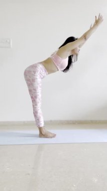 Yoga yapan sağlıklı bir kızın, chakrasana veya tekerlek pozu gibi poz verdiği bir video..