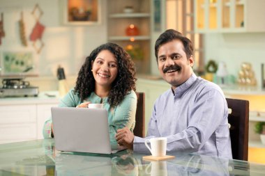 Genç çift kameranın önünde çay içerken gülümsüyor.