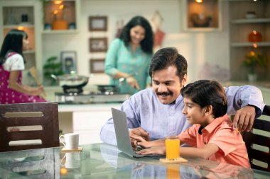 Baba Oğul 'a okul ödevi için yeni bir dizüstü bilgisayar kullanmasında yardım ediyor.