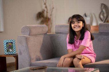 Güzel kız kameranın önünde poz verirken koltukta oturuyor.