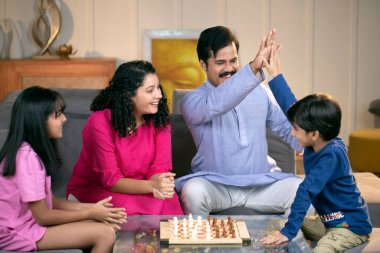 Sevimli aile evde satranç oynuyor.