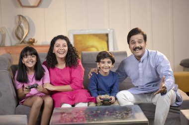 Çocuklar evde aileleriyle video oyunu oynuyor.