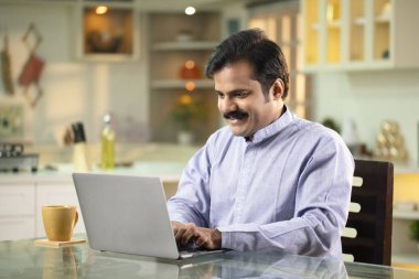 Bıyıklı Adam internette sörf yaparken çaydan zevk alıyor.