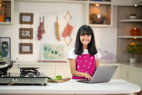 Asyalı kız mutfakta kameranın önünde dururken gülümsüyor.