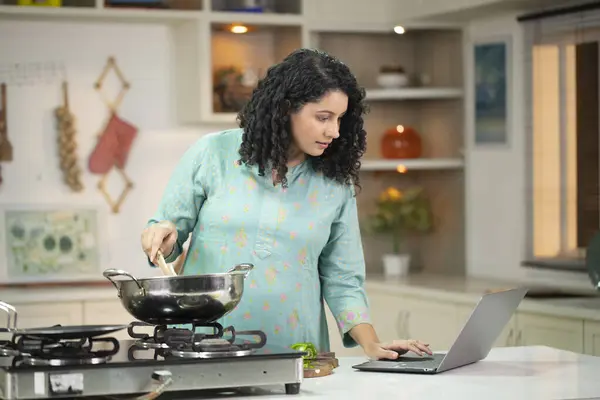 Ev hanımı laptopta sağlıklı salata tarifi okuyor.