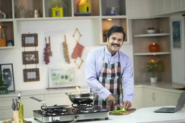 Zarif Adam kamera önünde poz verirken sebze kesip gülümsüyor. 